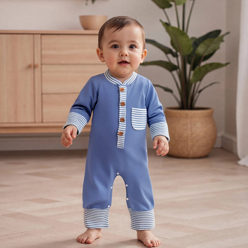 Hudson Button-Down Stripe Romper in blue worn by a standing baby in a cozy indoor setting, featuring button details and a playful front pocket.