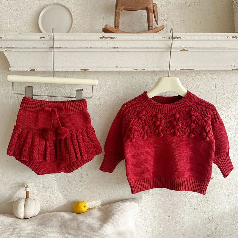 Stylish display of the deep red pullover and toddler skorts hanging, showcasing the adorable Popcorn Knit design.