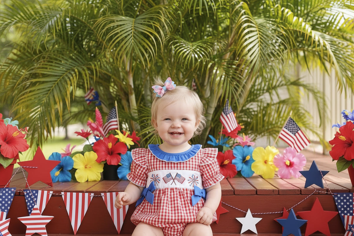 Child wearing a red checkered outfit with blue accents and American flags, sitting on a wooden step.