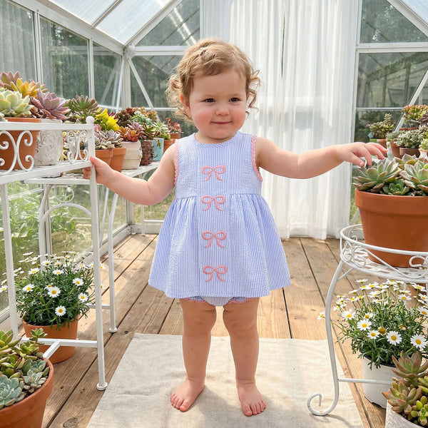 Toddler girl wearing Little Bows Seersucker Embroidered Dress and Bloomer Set with Palm Beach pink bows.
