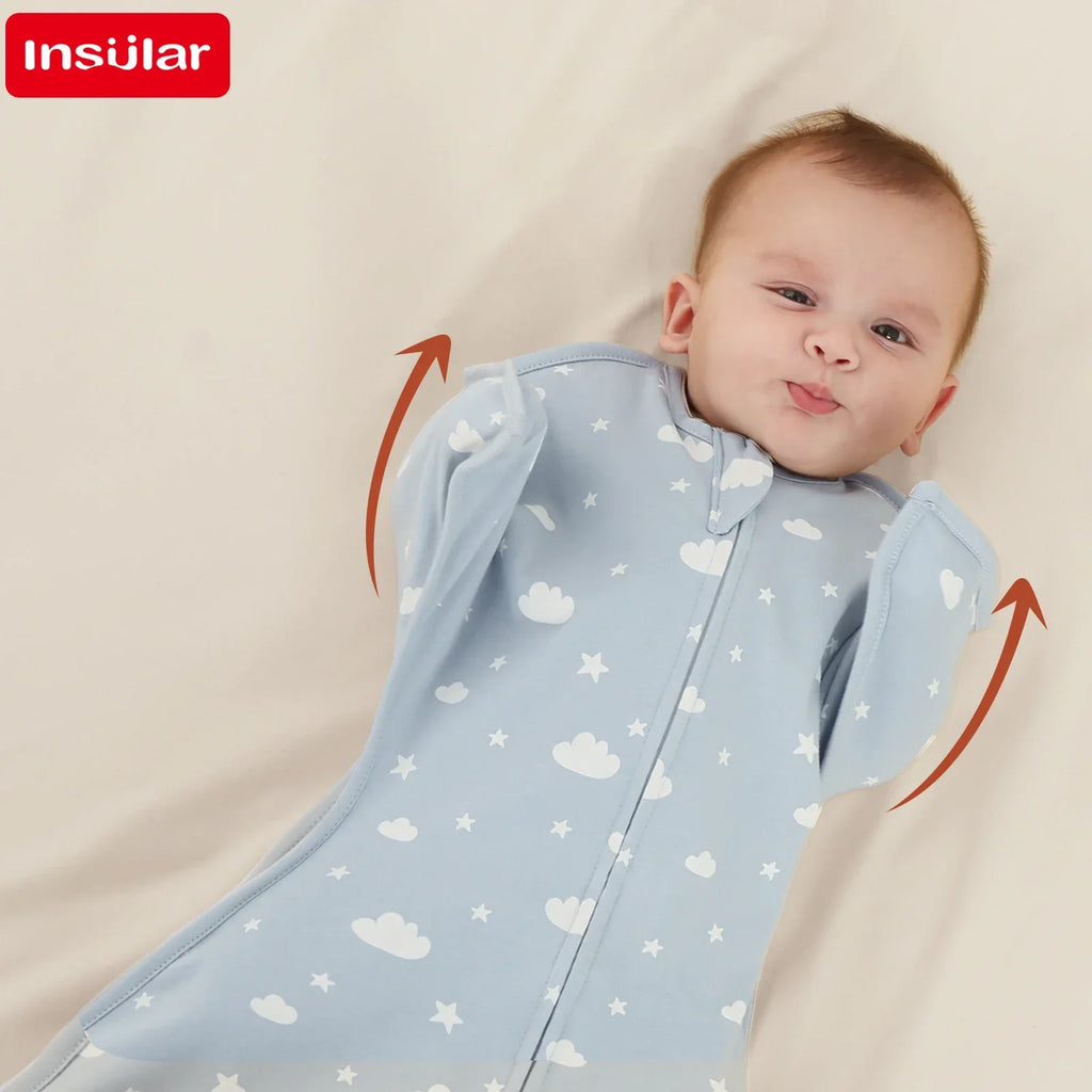 Adorable baby smiling while lying with arms raised, wrapped in a breathable cotton lightweight baby sleep sack in blue with cloud patterns.