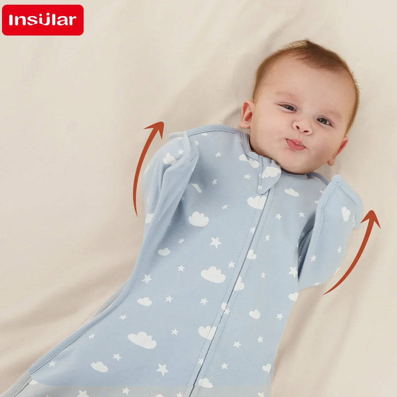 Adorable baby smiling while lying with arms raised, wrapped in a breathable cotton lightweight baby sleep sack in blue with cloud patterns.
