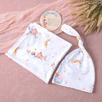 White baby swaddle and tied headband set featuring teddy bears, rainbows, and stars on a pink background with an "I'm here" tag.