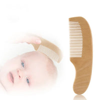 Personalized wooden baby comb, infant grooming accessory shown with baby.