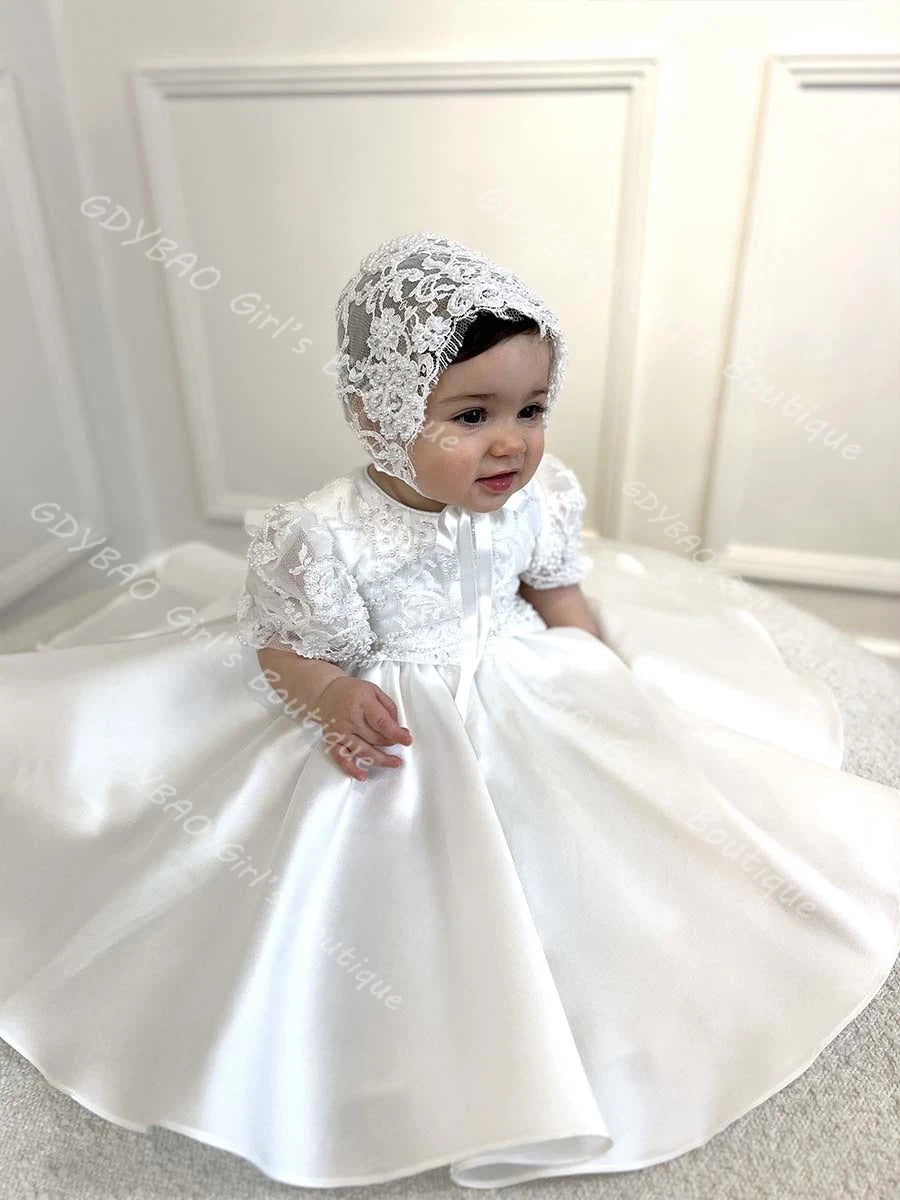 Hannah White Special Occasion Beaded Lace Gown with Matching Bonnet on a baby girl; white floor-length dress with bow