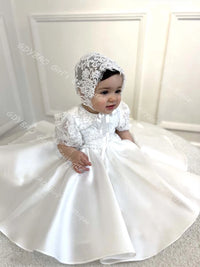 Hannah White Special Occasion Beaded Lace Gown with Matching Bonnet on a baby girl; white floor-length dress with bow
