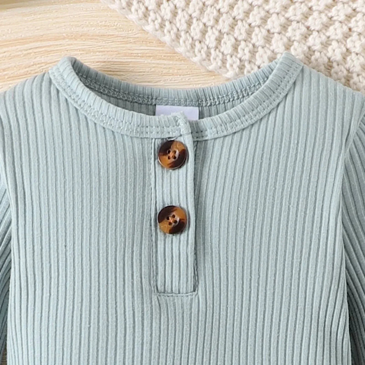 close up of light green ribbed romper with brown buttons for babies and kids
