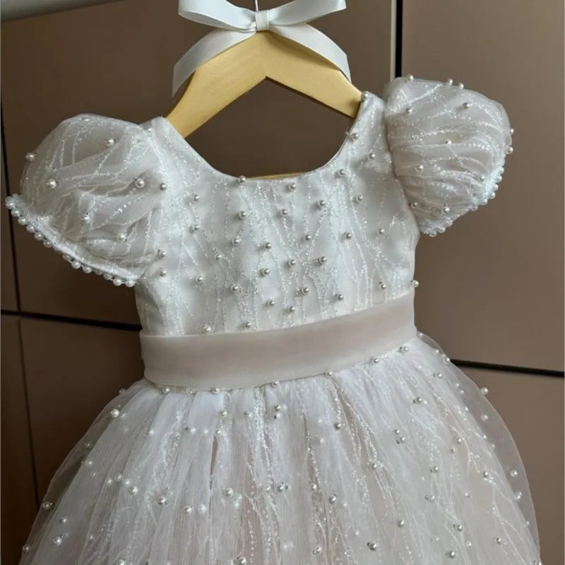 White beaded dress on a hanger against a neutral background