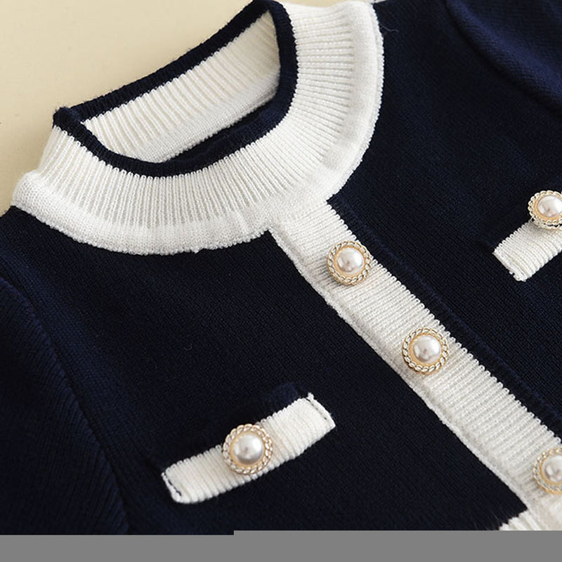 Close-up view of the Chic Melinda Knit Dress neckline featuring a navy and white design with faux pearl button accents.