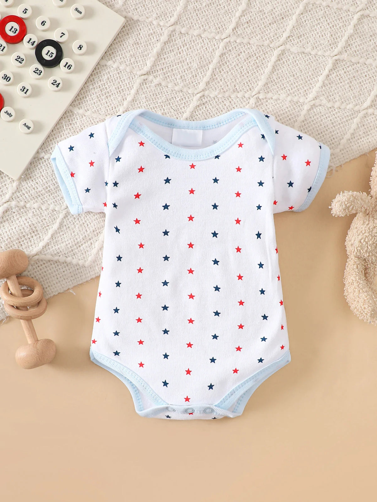 Star-print white baby bodysuit with red and blue stars and light-blue trim.