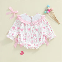Baby romper with pink bows on a beige background