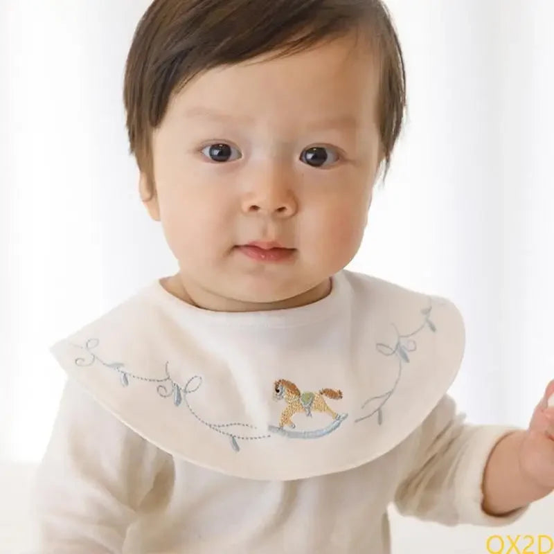 Embroidered waterproof cotton baby bib featuring a rocking horse design with snap closure for mealtime protection.