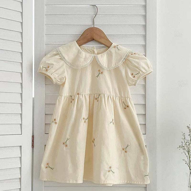 Sweet Lydia Little Girl's Dress in a soft beige hue with charming embroidered daisies, designed for comfort and style for young girls aged 2 to 6.