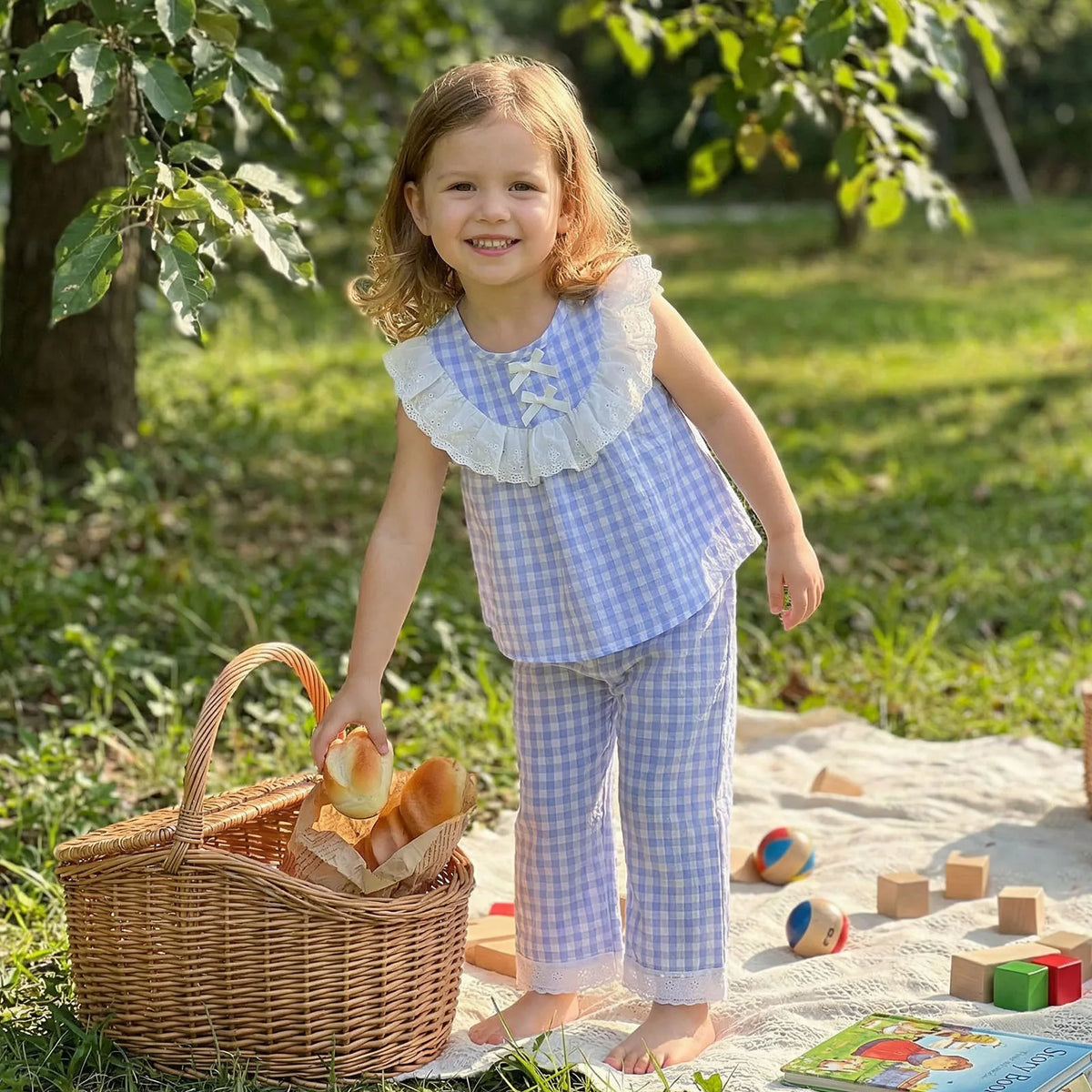 Little girl in Boca blue Eyelet and Checks 2-Piece Pant Set with lace collar, outdoors.