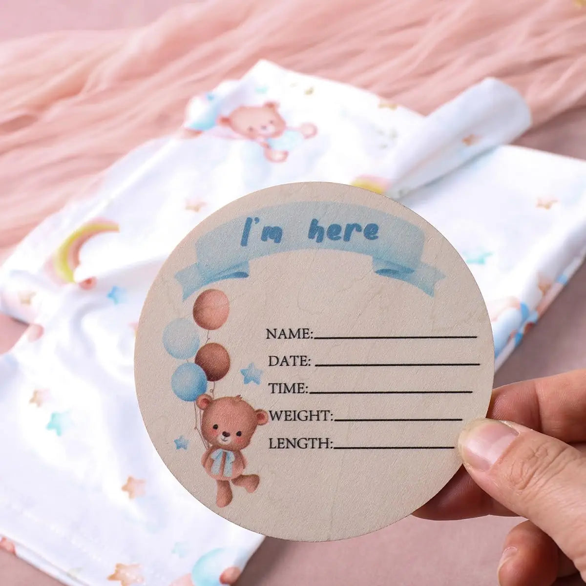 Round "I'm here" baby milestone tag with teddy bear and balloons for swaddle set, listing name, date, time, weight, and length.