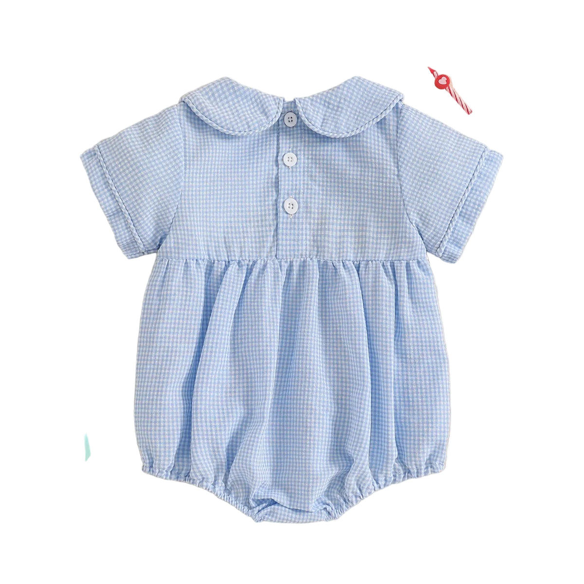 Blue checkered baby romper on a beige background with decorative items.
