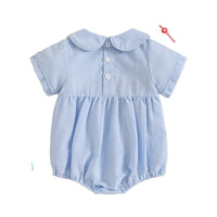 Blue checkered baby romper on a beige background with decorative items.