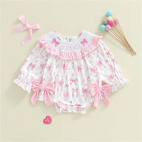 Baby romper with pink bows and ruffles on a beige background