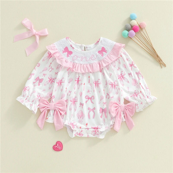 Baby romper with pink bows and ruffles on a beige background