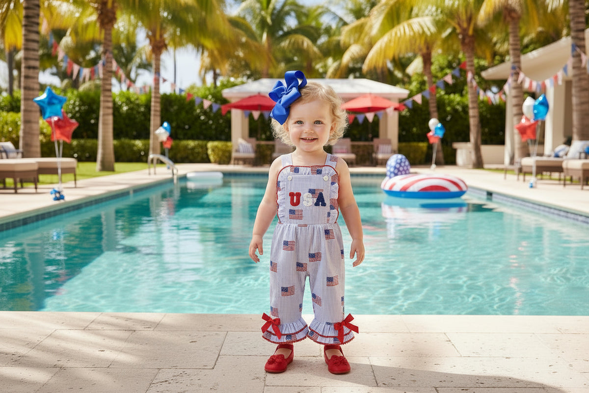 Child wearing a 'USA' themed romper in a cozy living room.