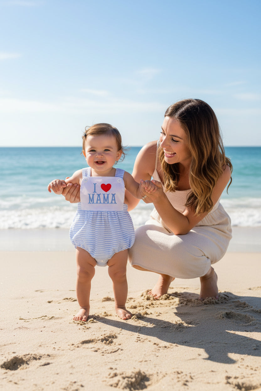 Toddler on the beach with her mother in blue romper overalls
