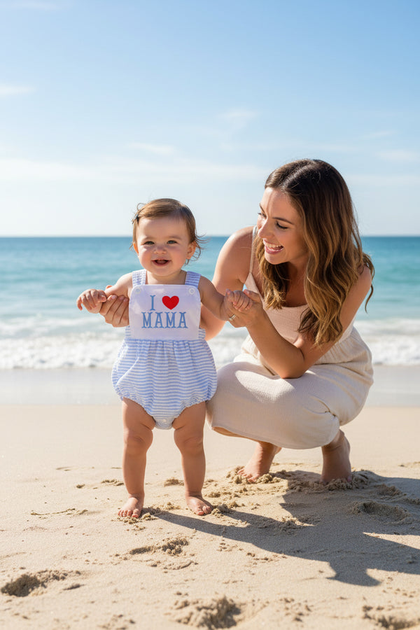Toddler on the beach with her mother in blue romper overalls