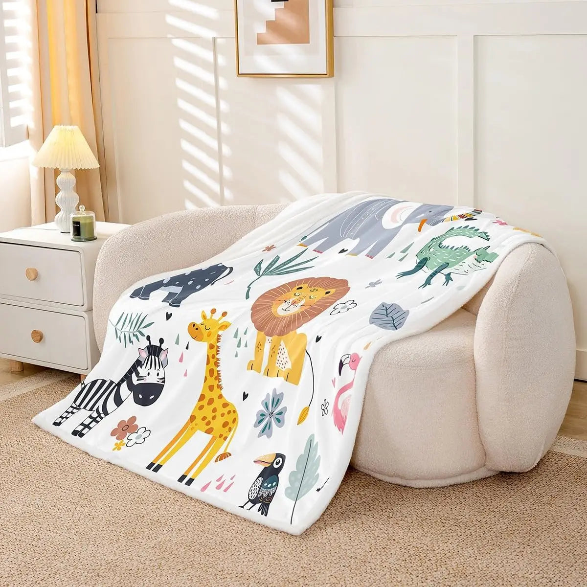 Jungle Rumble double-sided children's blanket, 100% polyester fleece, safari animals on white, draped over beige sofa.