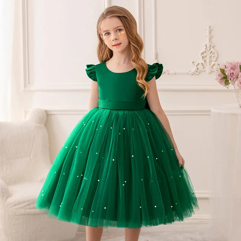 A girl wearing a rich green 'Chantelle-Elise' V-Back Occasion Dress, showcasing its elegant tulle layers and perfect fit for special occasions.