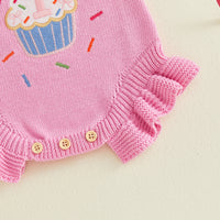 Pink knitted baby romper with cupcake embroidery and buttoned hem.