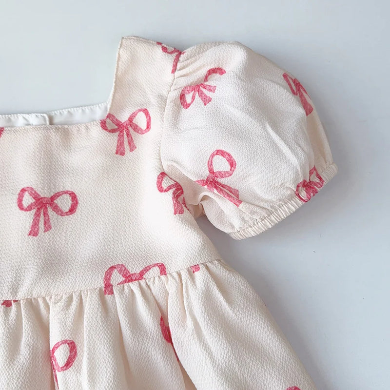 Close-up of the puff sleeve design on the Sweet Little Bows Party Dress, highlighting the soft fabric and charming pink bows.