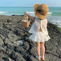 Little girl wearing Wentworth white Summer and Lace 2-Piece Skort and Top Set on rocky beach with straw hat.