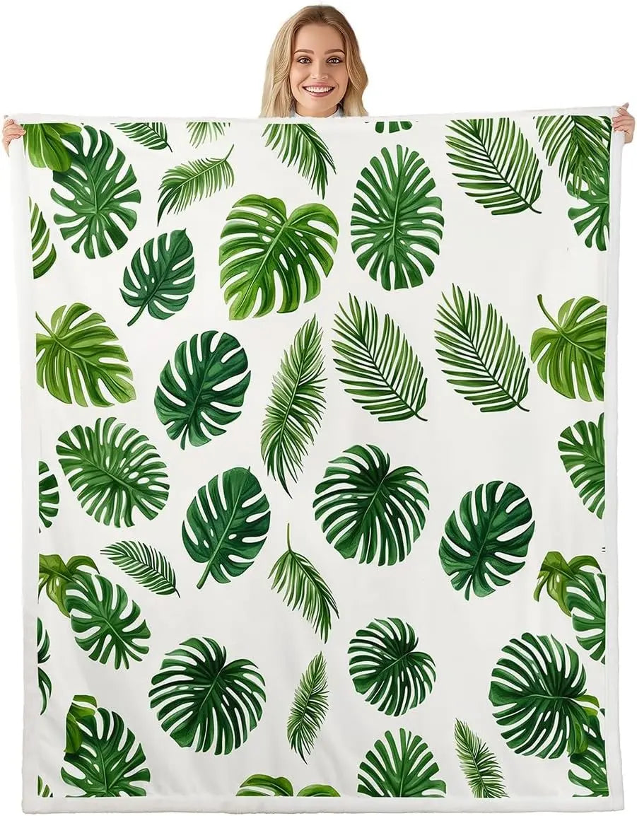 Jungle Rumble double-sided children's blanket with tropical leaf print on white, held by smiling person.