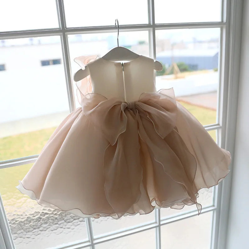 Back view of the Gwendolyn Tulle Special Occasion Dress - Chic Beige, showcasing a large tulle bow and a zippered back, perfect for special occasions.