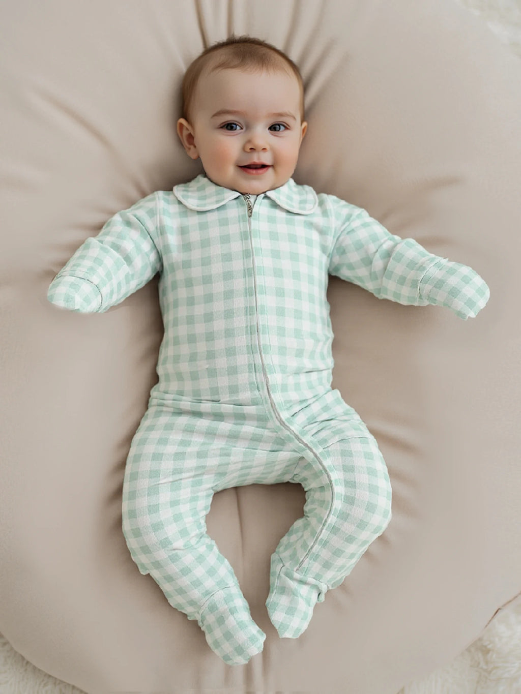 Baily Checked Footie in Palm Green color, featuring a baby smiling while wearing the cozy outfit, showcasing the Peter Pan collar and zippered front.