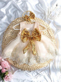 Infant sequined V-back dress with an oversized gold bow and matching headband, pink satin bodice, lace trim.