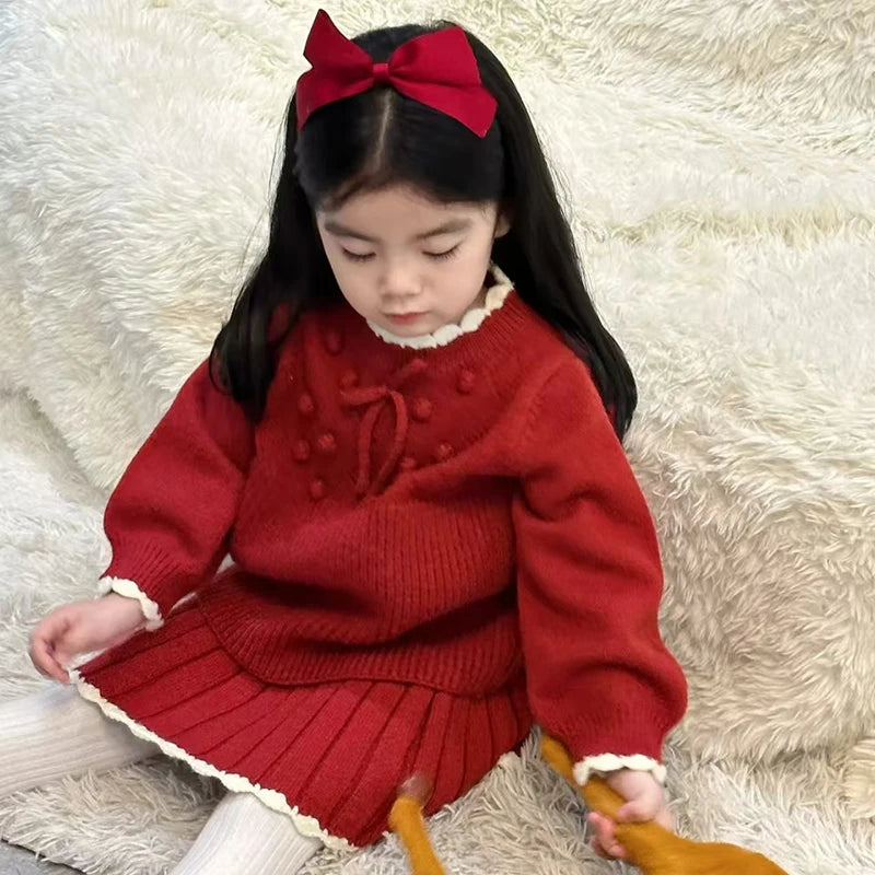 Sweet Anna Knit Skirt Set for Girls, displaying a young girl in a cozy red outfit with a pleated skirt, perfect for festive family gatherings.