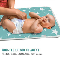 Baby on a turquoise star-print waterproof changing pad, soft cotton cover for diaper changes.