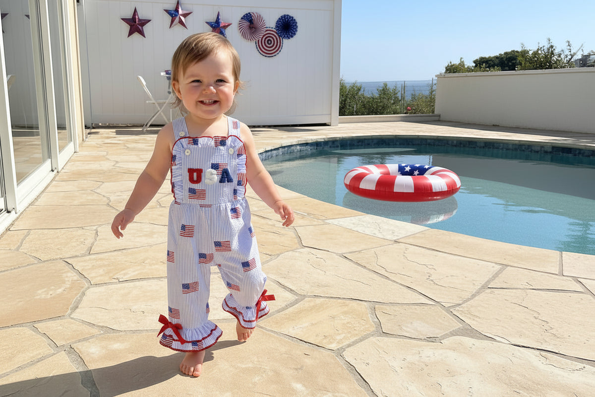 Child wearing a patriotic outfit with American flag patterns by a poolside.