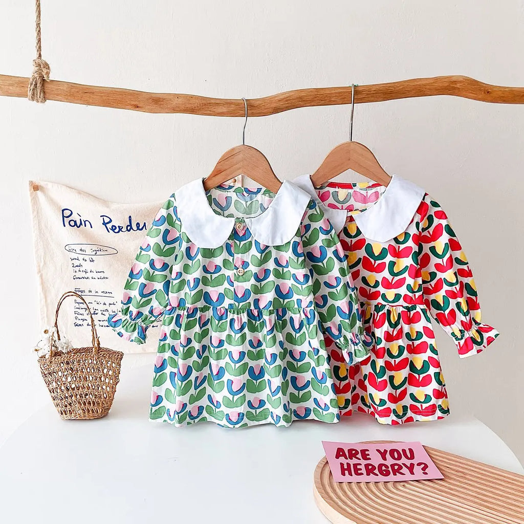 Two 'Mariella' Floral Print Peter Pan Collar Dresses displayed on hangers, one in green floral pattern and the other in red floral pattern, perfect for little girls.