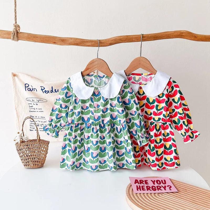 Two 'Mariella' Floral Print Peter Pan Collar Dresses displayed on hangers, one in green floral pattern and the other in red floral pattern, perfect for little girls.