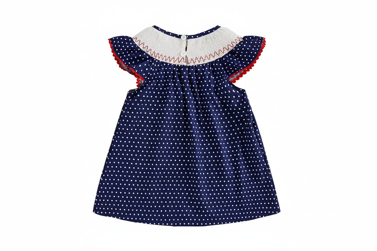 Navy blue dress with white polka dots and red trim on a beige background