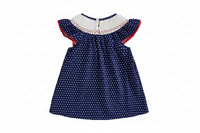 Navy blue dress with white polka dots and red trim on a beige background