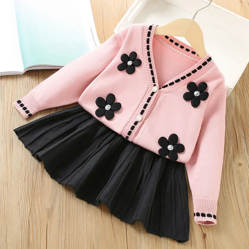 Vanessa floral knitted cardigan with black flower appliques and matching black pleated skirt two-piece set in pink.