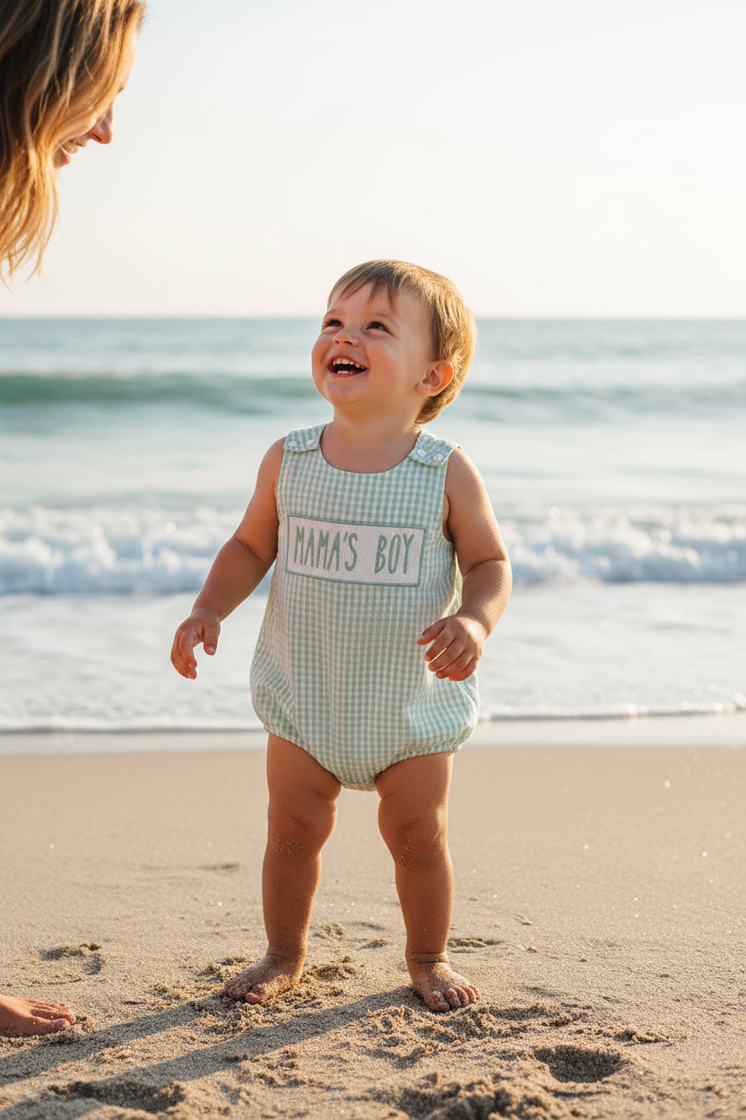 Green checkered baby romper with 'MAMA'S BOY' text on a white background