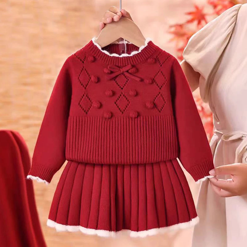 Charming Anna Knit Skirt Set for Girls in a vibrant red color, showcasing a long-sleeve top with decorative elements and a matching pleated skirt.