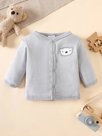 Gray baby cardigan with bear face patch and front snaps, laid on beige background with toys.
