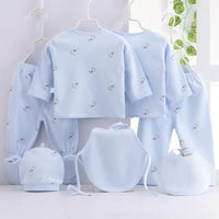 Playful giraffe-themed 7-piece newborn layette set in pale blue with giraffes; includes hats, bibs, booties, and pants.