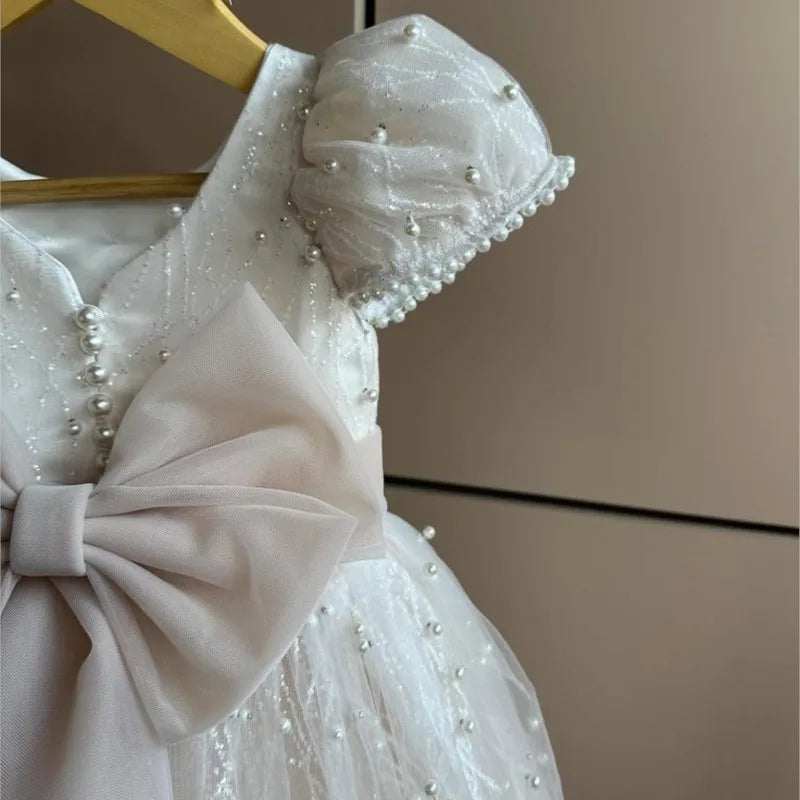 White dress with pearl embellishments on a hanger against a neutral background