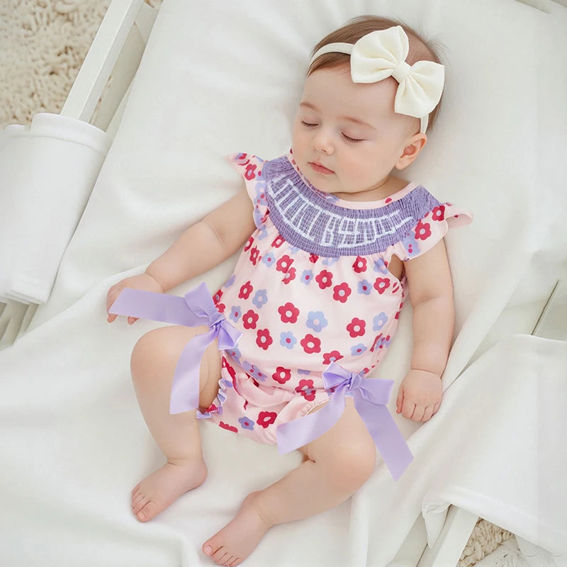 Floral romper for babies in pink with purple ruffle collar and lavender bows, newborn size