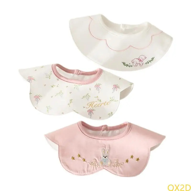 3-Piece embroidered baby bibs set in pink and white featuring bear, floral, and rabbit designs with snap closures.